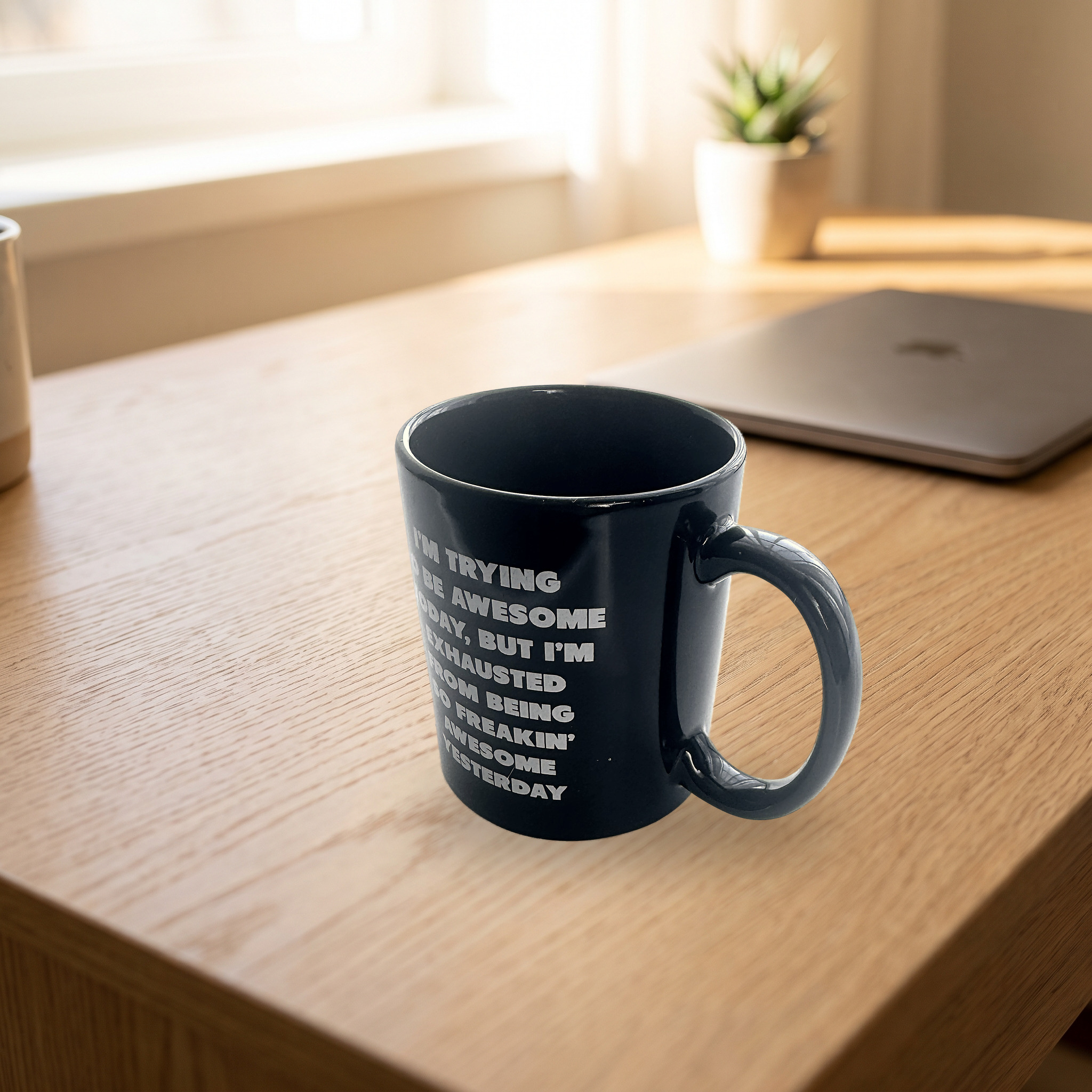 The mug on an oak desk next to a laptop